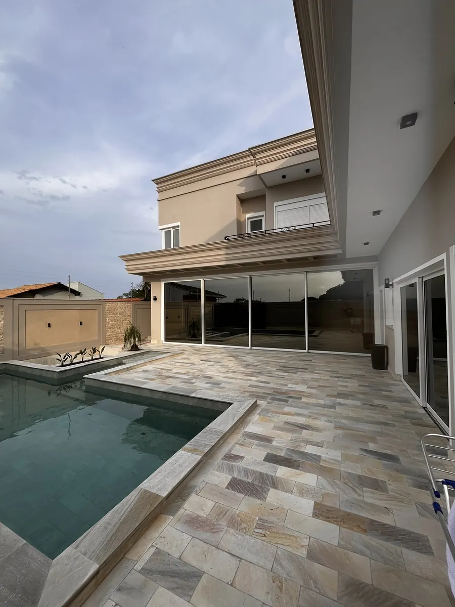 Casa de alto padrão com grandes portas de vidro voltadas para o jardim e a piscina